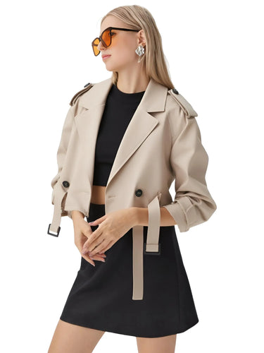 Woman wearing a khaki crop trench coat over a black outfit on a white background